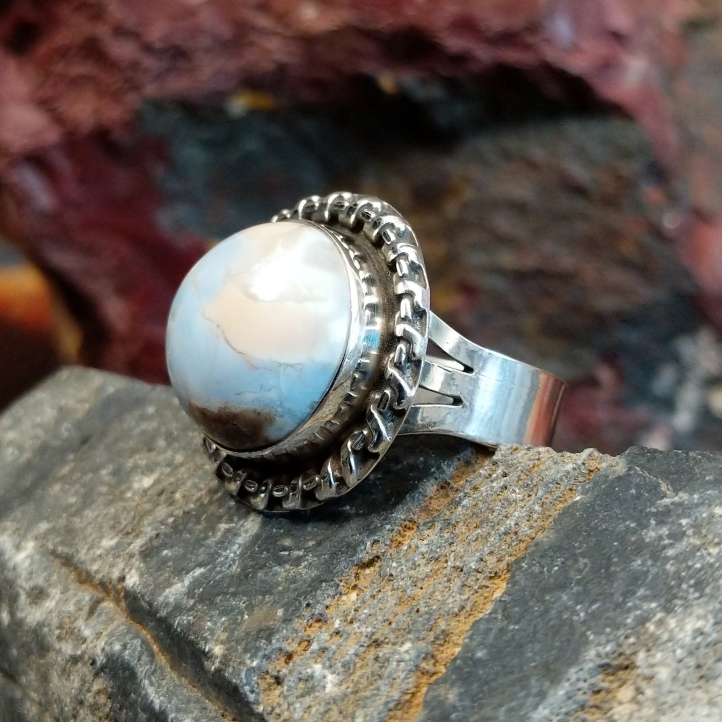 Ring features a large, dome-shaped blue opal set in a twisted silver band.