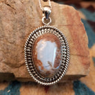 Sterling silver pendant with Arizona blue opal set in the oval bezel, framed by ornate silverwork.