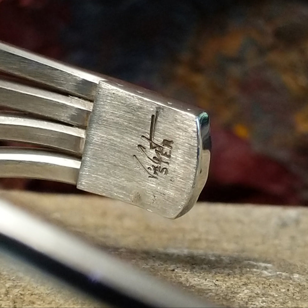 The artist's signature is on the tip of the sterling silver band.