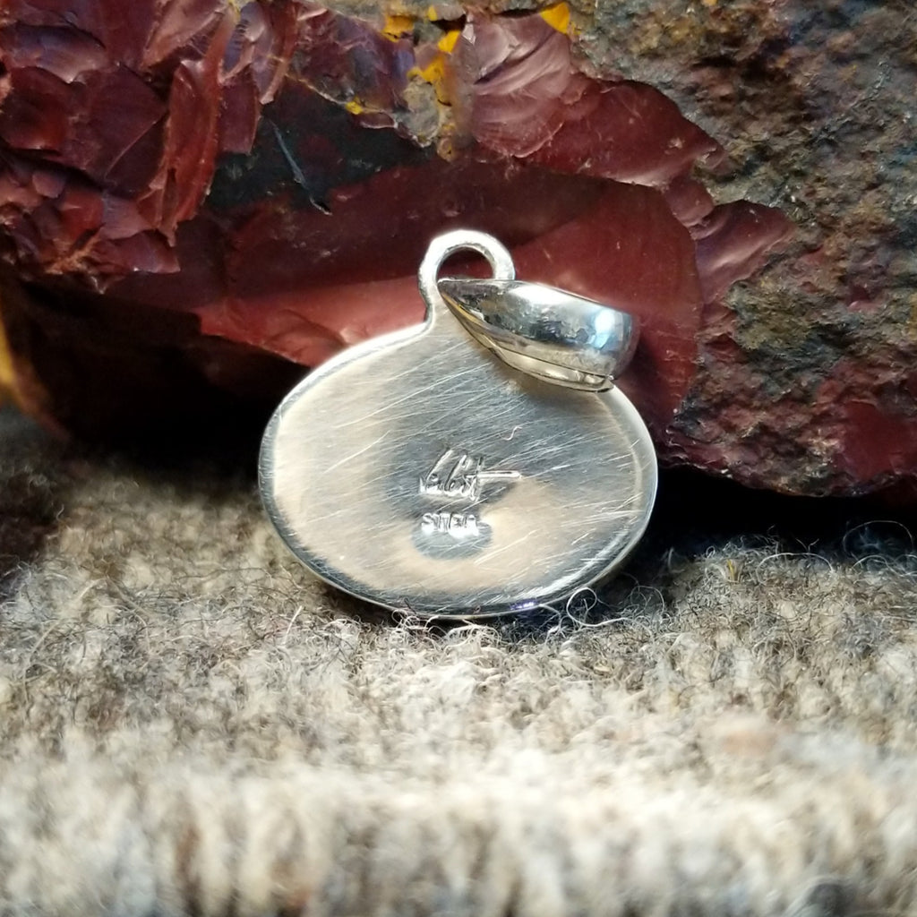 The sterling silver backing features the artist's signature.