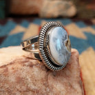 Sterling silver ring with Arizona blue opal set in the oval bezel, framed by ribbed silverwork.
