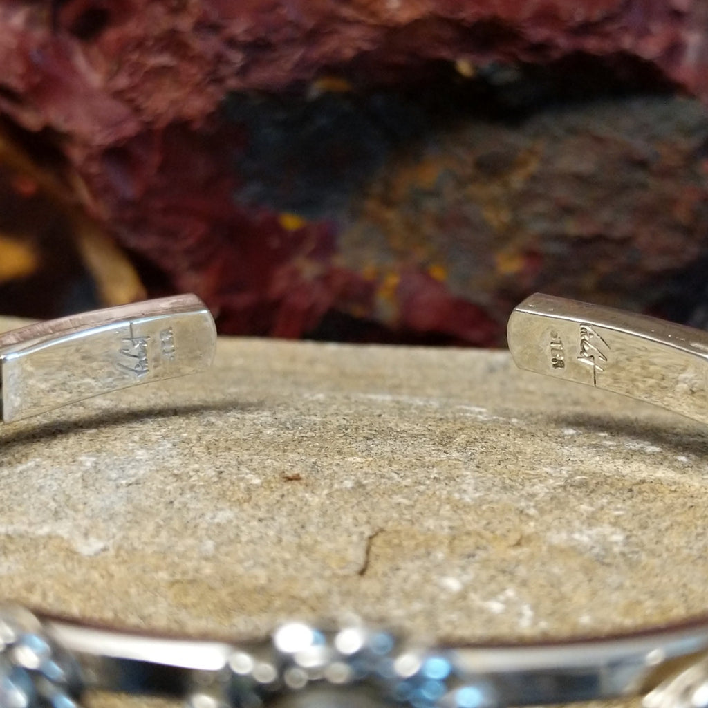 The artist's signature is on engraved on the tip of the band.
