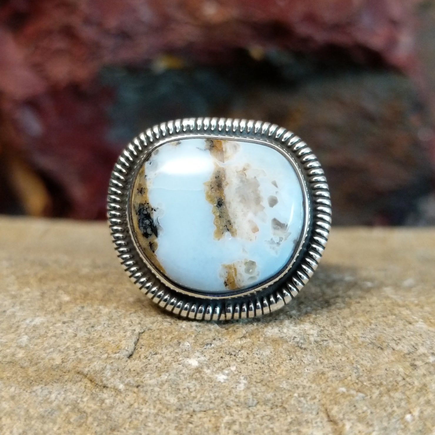 A sterling silver ring featuring a cushion-cut Arizona Blue Opal framed by a twisted rope bezel.