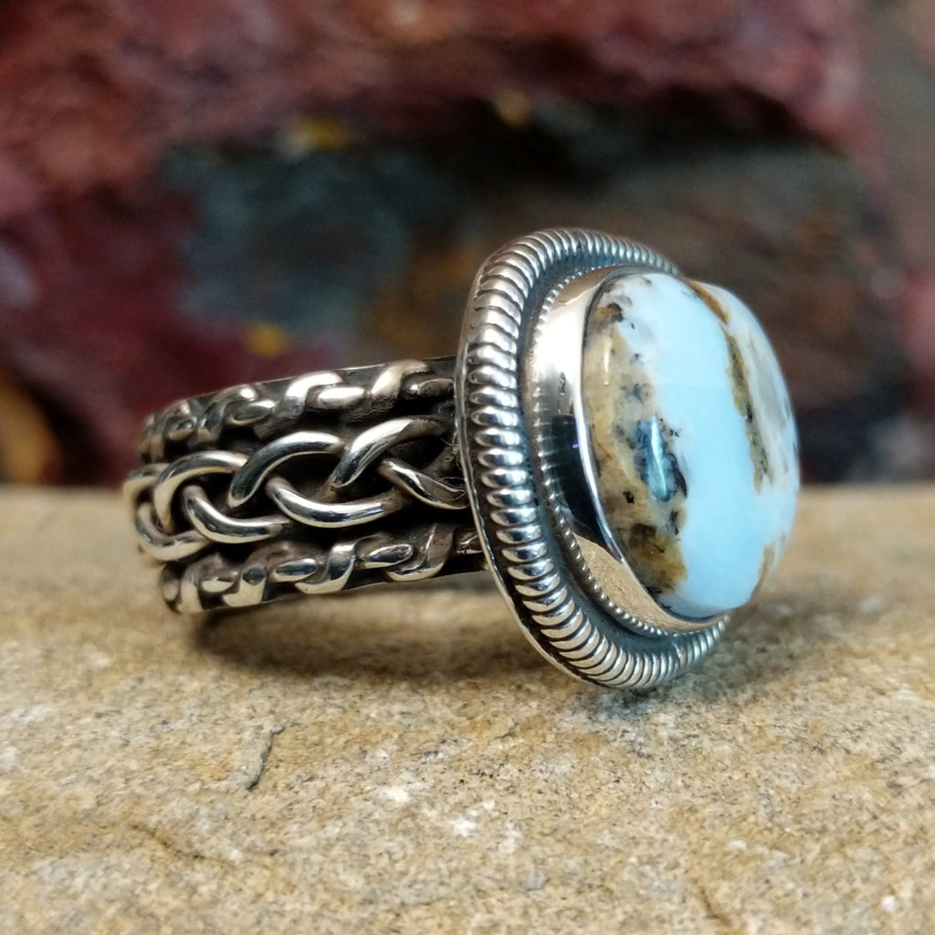 A sterling silver ring featuring a cushion-cut Arizona Blue Opal framed by a twisted rope bezel.