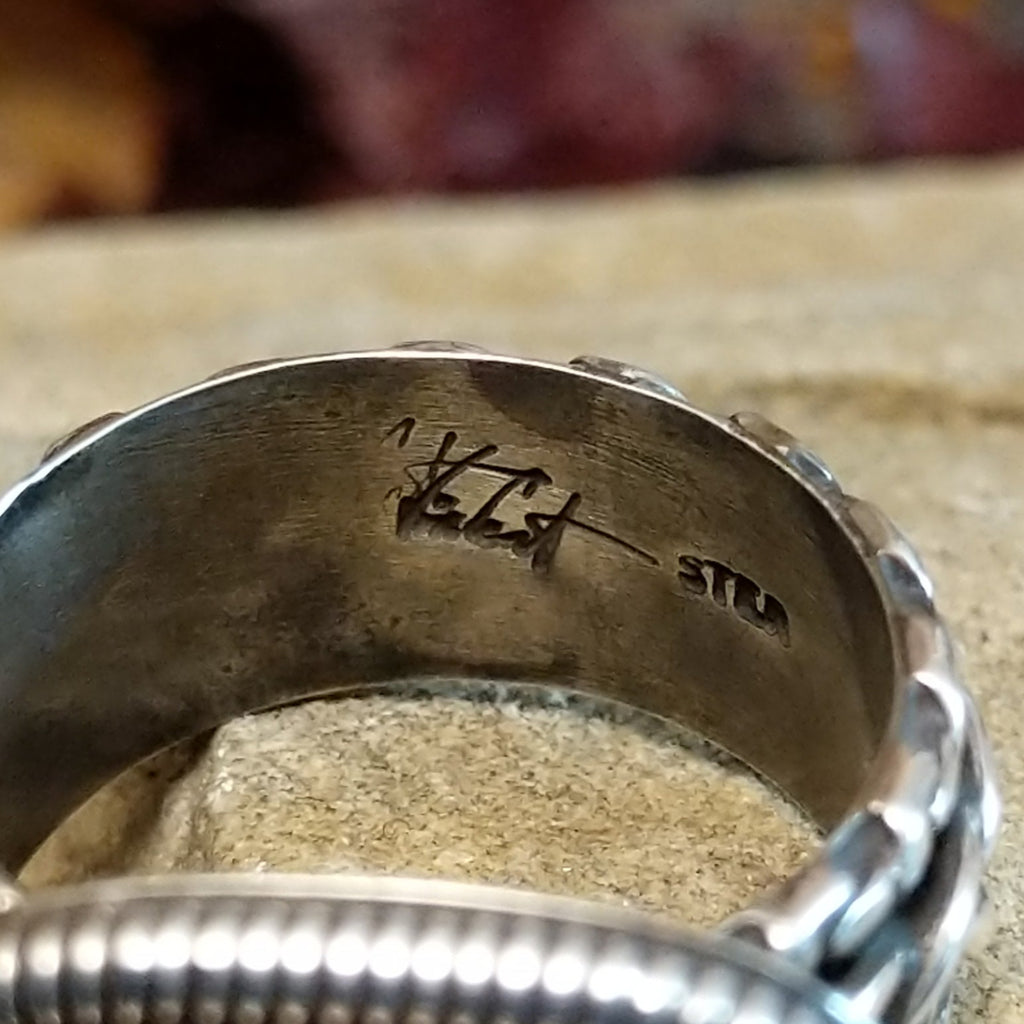 The artist's signature is etched into the band.
