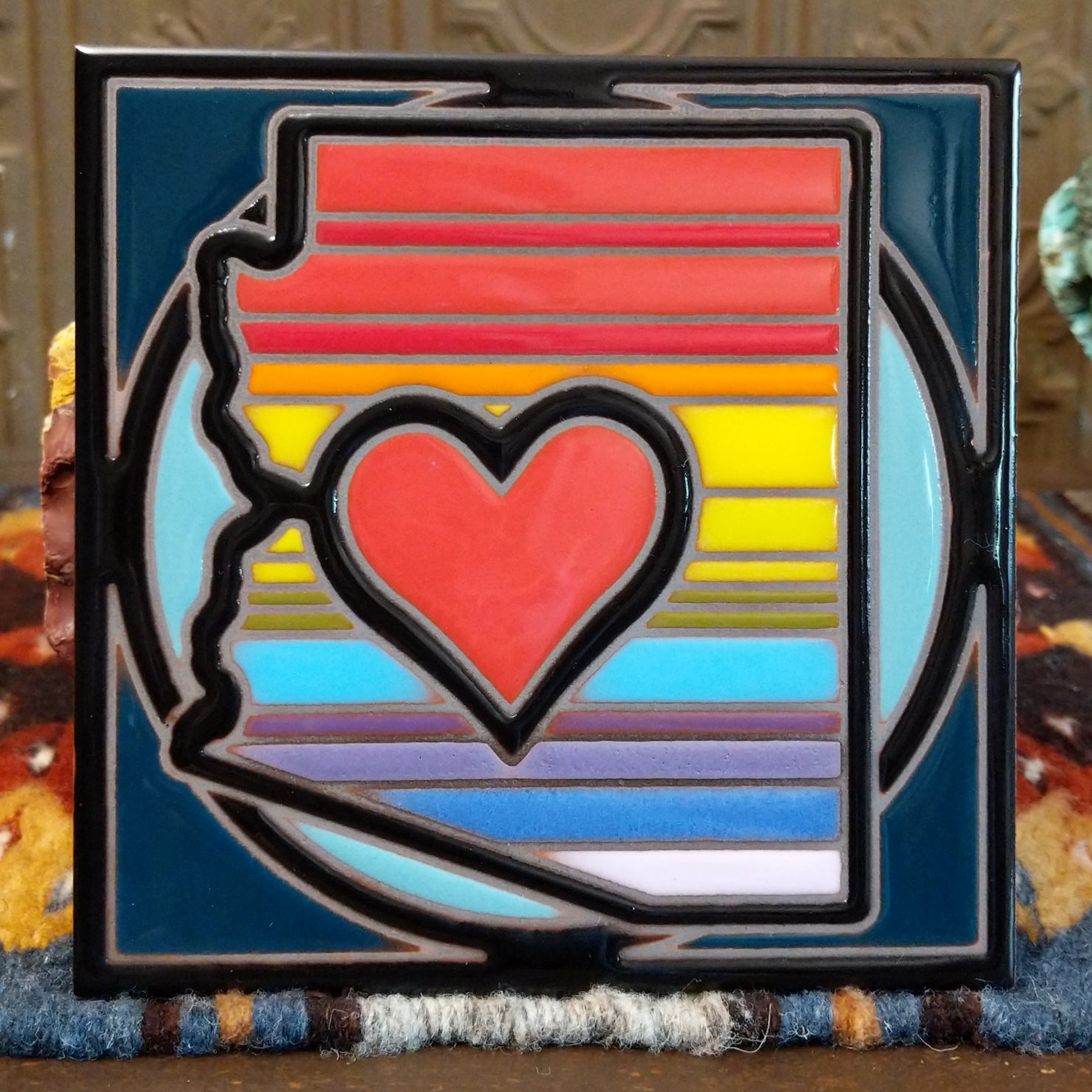 Ceramic tile featuring a stylized Arizona map with a red heart and colorful stripes on a dark border.