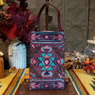 Aztec Club Bag by Bamboo Trading featuring intricate turquoise, pink, plum, and purple geometric patterns with diamond motifs, embroidered details, shimmering beadwork, sequins, and a coordinating burgundy shoulder strap.