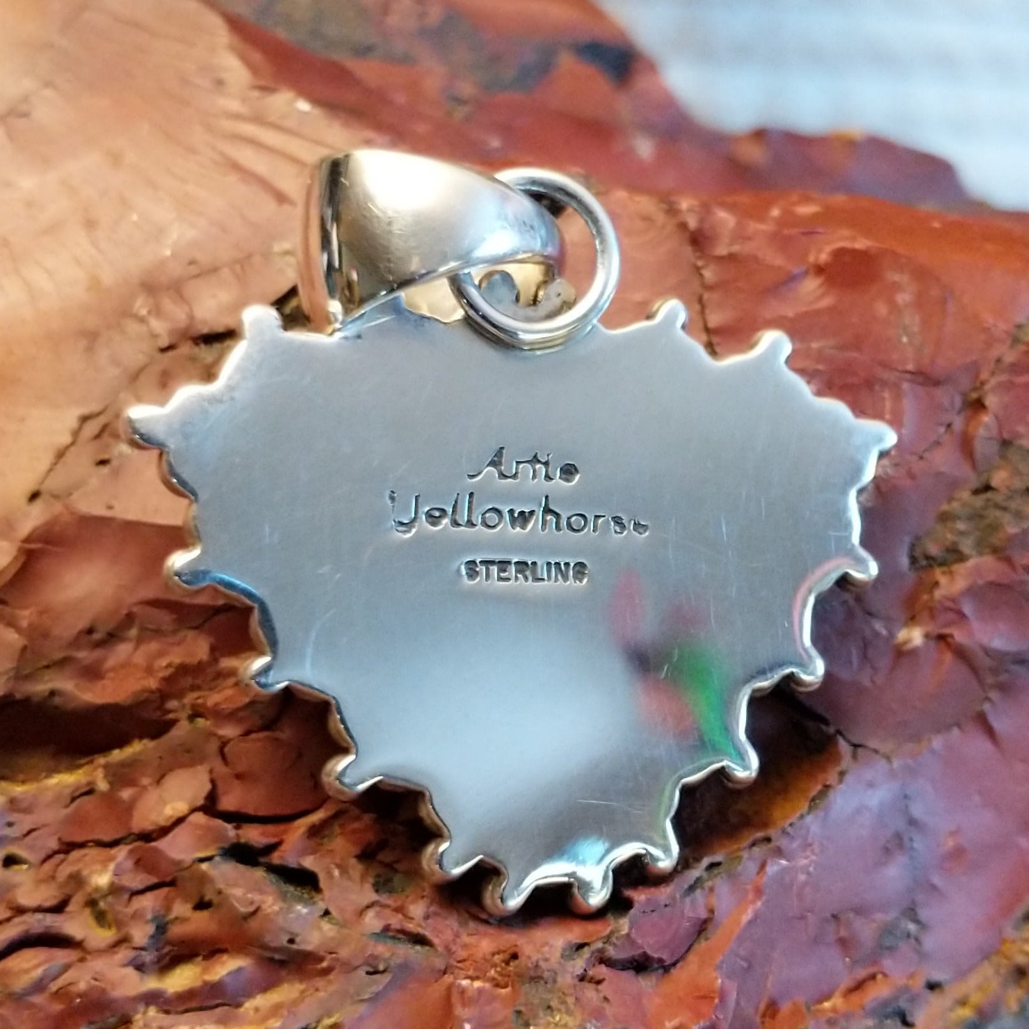 The back of the pendant features the artisan's stamped signature.