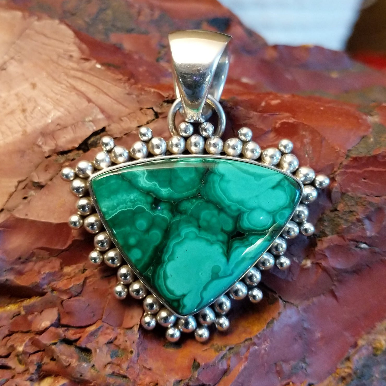 Triangular sterling silver pendant with malachite set within the bezel and dotted accents.