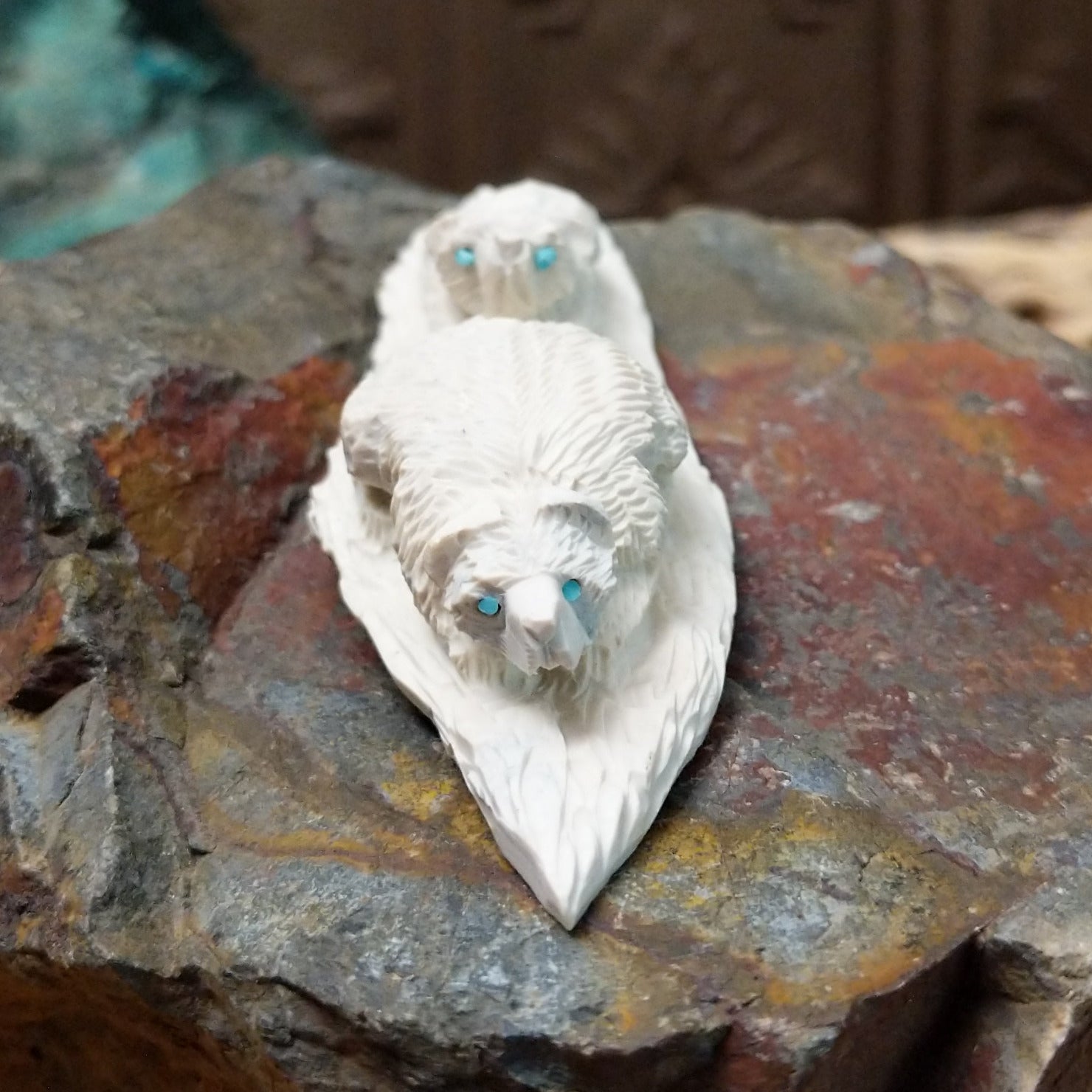 Zuni bear cub fetish carving by Adrian Cachini featuring two white stone bears with turquoise inlaid eyes resting on a carved base.