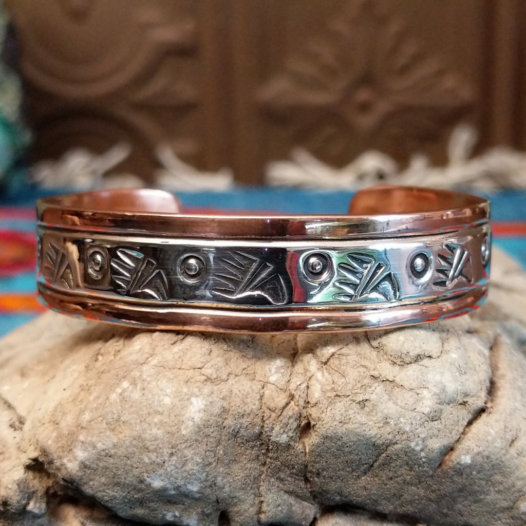 Copper and sterling silver cuff with bear paw patterned stamps.
