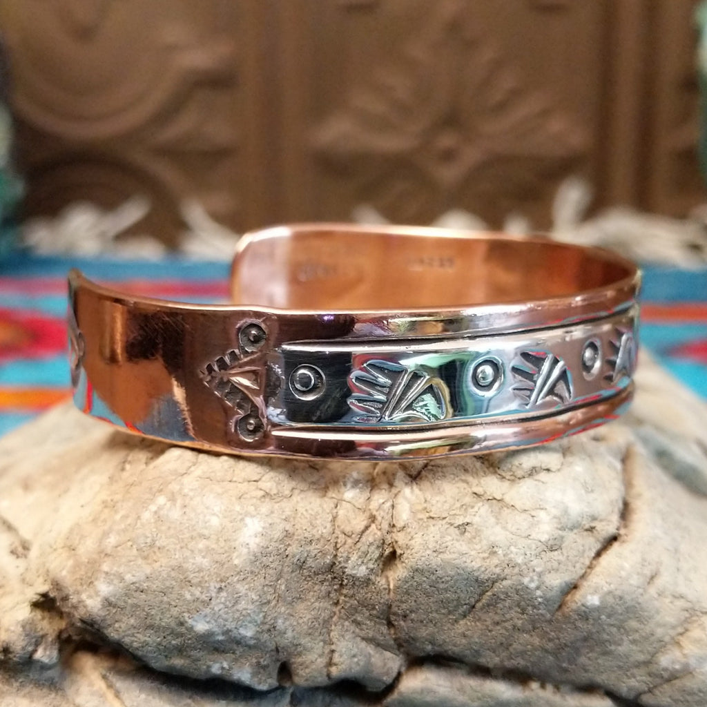 Copper and sterling silver cuff with bear paw patterned stamps.