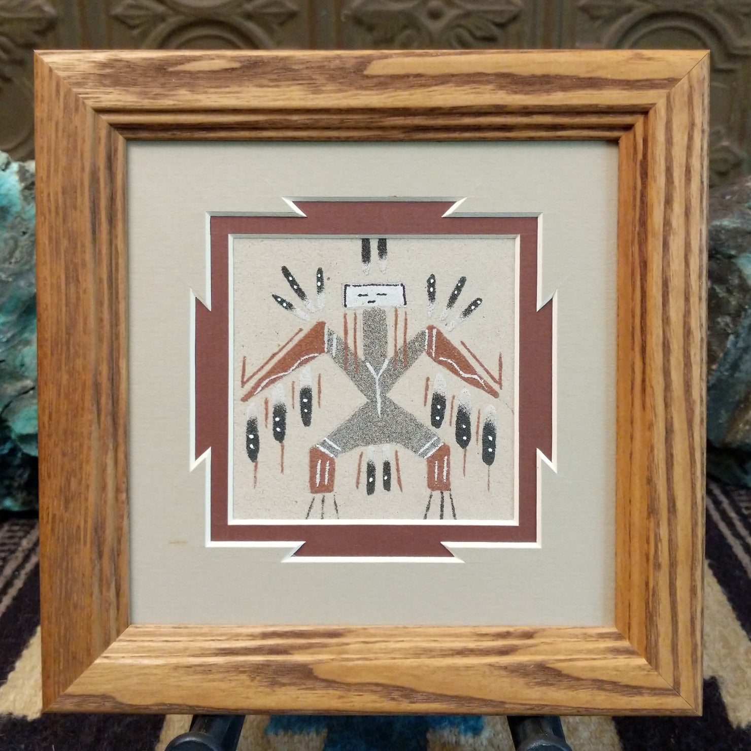 Framed Navajo sand painting of a Bird Yei with symbolic motifs.