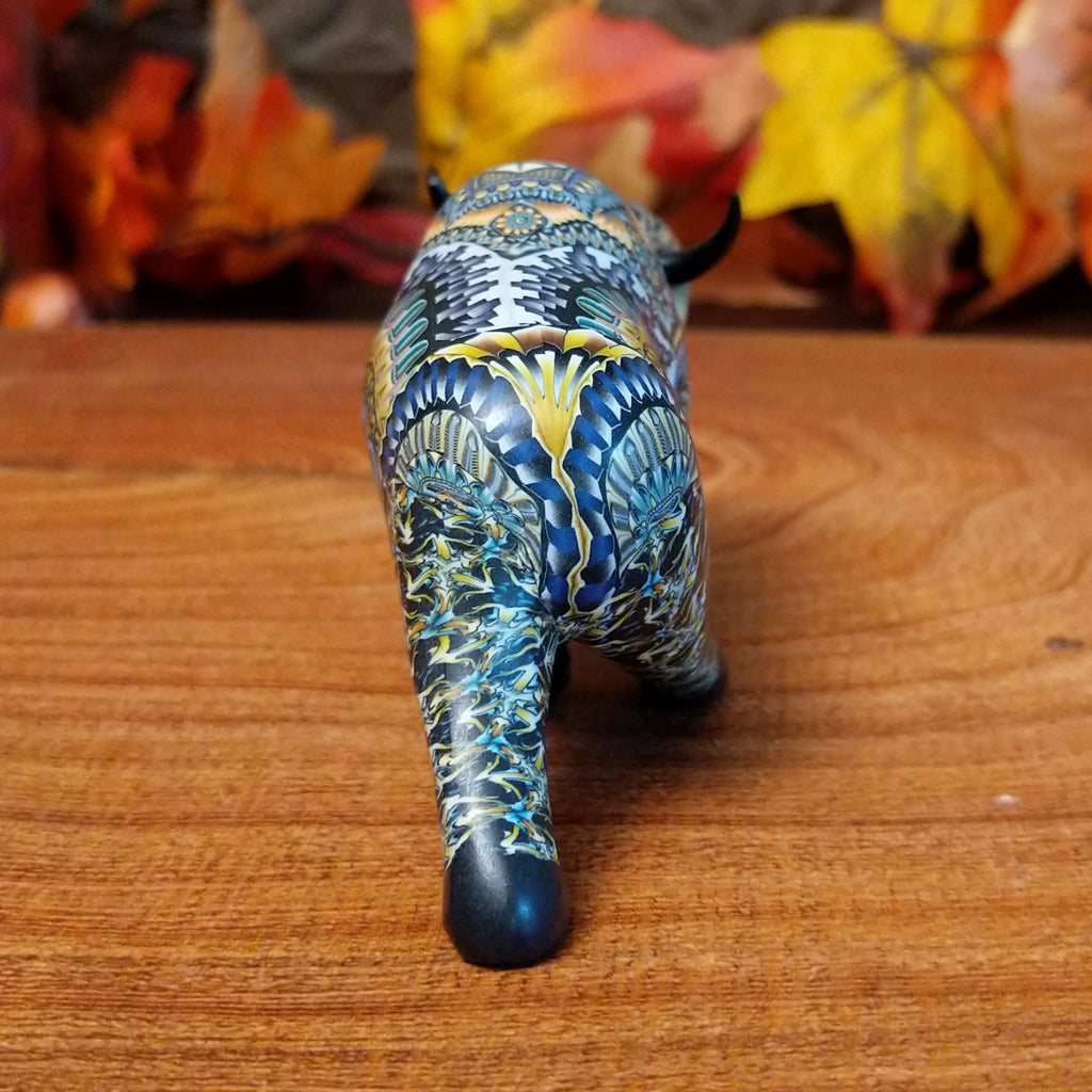 Decorative figurine of a buffalo with intricate blue and yellow patterns on a wooden surface.