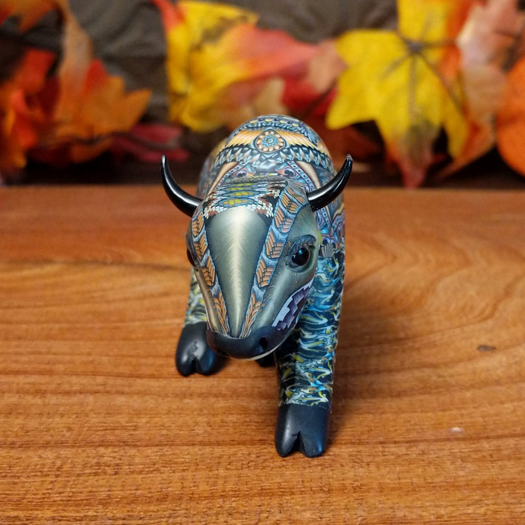 Decorative figurine of a bison on a wooden surface with autumn leaves in the background