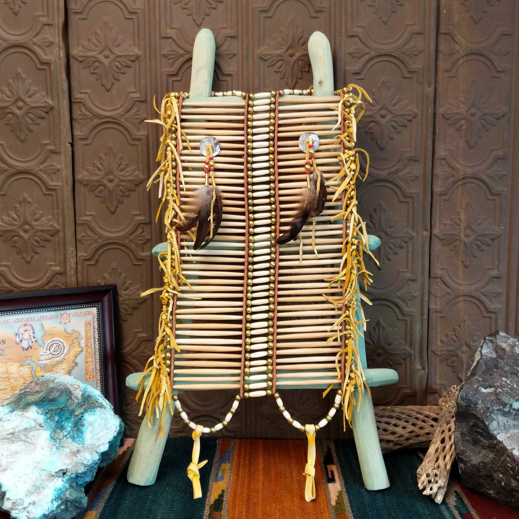 Bison bone chest armor with feather and tied accents on the chest piece with brass and white beads all along the piece.