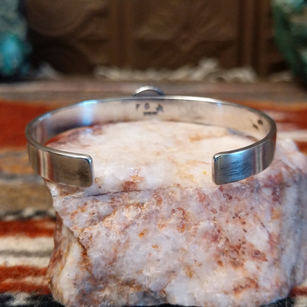 The cuff is brushed sterling silver.