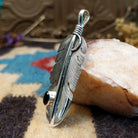 Sterling silver feather pendant with black onyx set in a small, round bezel.