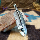 Sterling silver feather pendant with black onyx set in a small, round bezel.