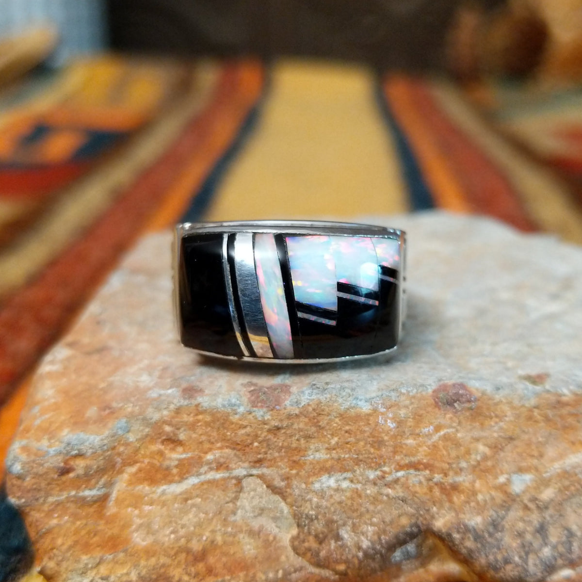 Black Onyx & Manmade Opal Ring by Kenneth Bitsie featuring geometric black onyx and iridescent manmade opal inlay set in a wide sterling silver band with a Southwestern design.