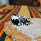 Black Onyx & Manmade Opal Ring by Kenneth Bitsie featuring geometric black onyx and iridescent manmade opal inlay set in a wide sterling silver band with a Southwestern design; side view.