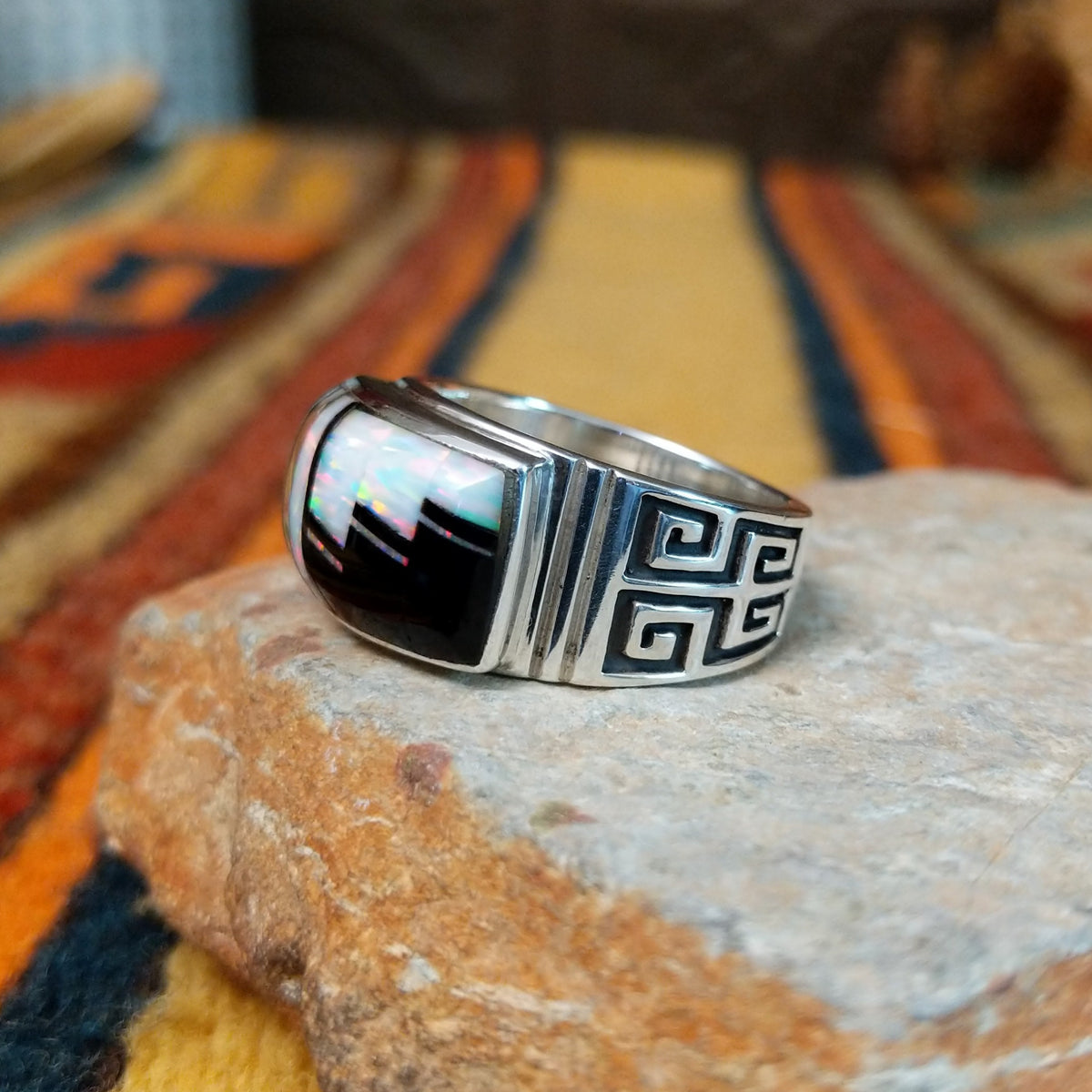 Black Onyx & Manmade Opal Ring by Kenneth Bitsie featuring geometric black onyx and iridescent manmade opal inlay set in a wide sterling silver band with a Southwestern design; side view.