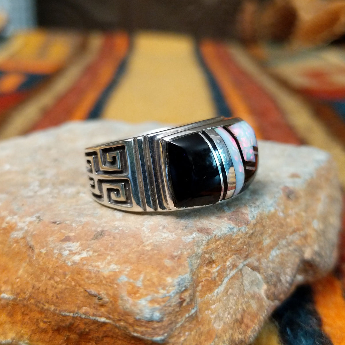 Black Onyx & Manmade Opal Ring by Kenneth Bitsie featuring geometric black onyx and iridescent manmade opal inlay set in a wide sterling silver band with a Southwestern design; side view.