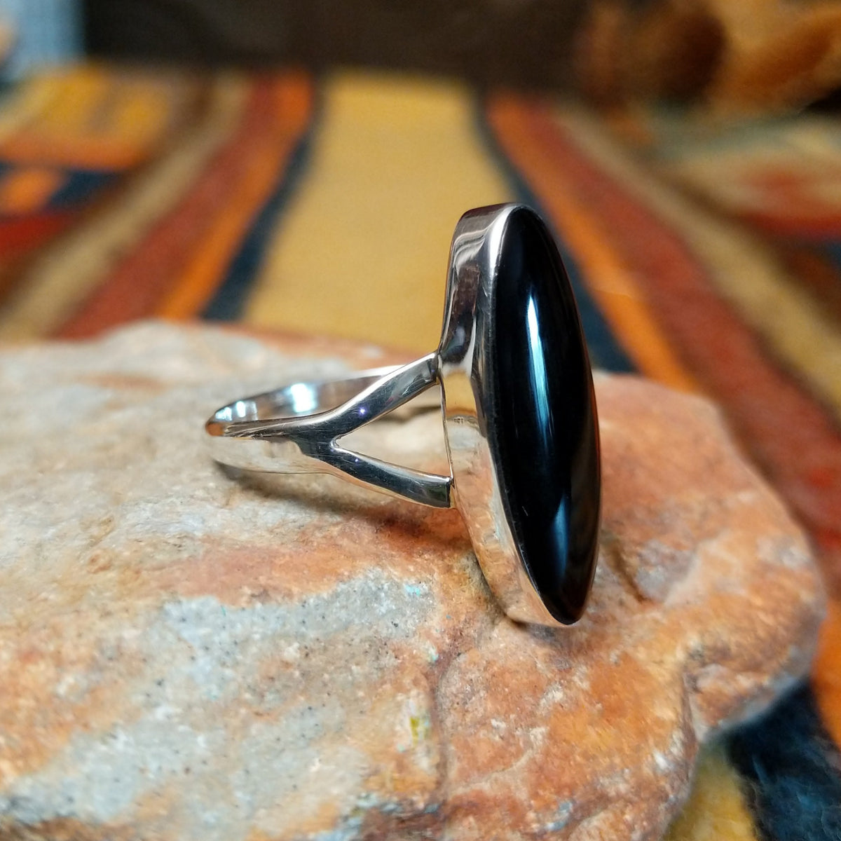 Black Onyx Ring by Cathy Webster featuring an elongated oval polished black onyx stone set in sterling silver with a smooth bezel and open split-shank band; side view.