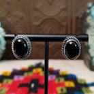Black Onyx Oval Earrings by Priscilla Smith featuring glossy oval black onyx cabochons set in polished silver with detailed twisted rope-style borders.