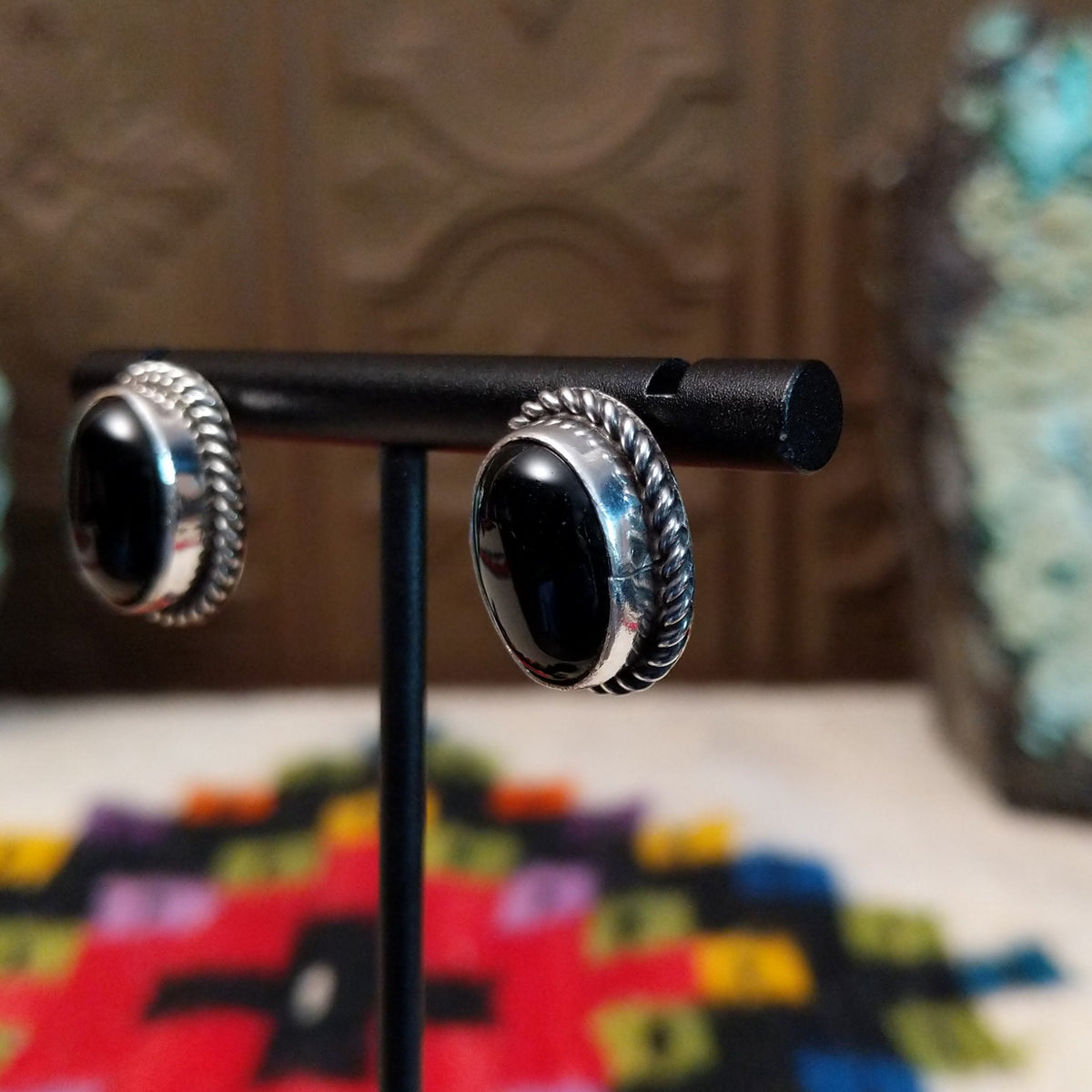 Black Onyx Oval Earrings by Priscilla Smith featuring glossy oval black onyx cabochons set in polished silver with detailed twisted rope-style borders; side view.