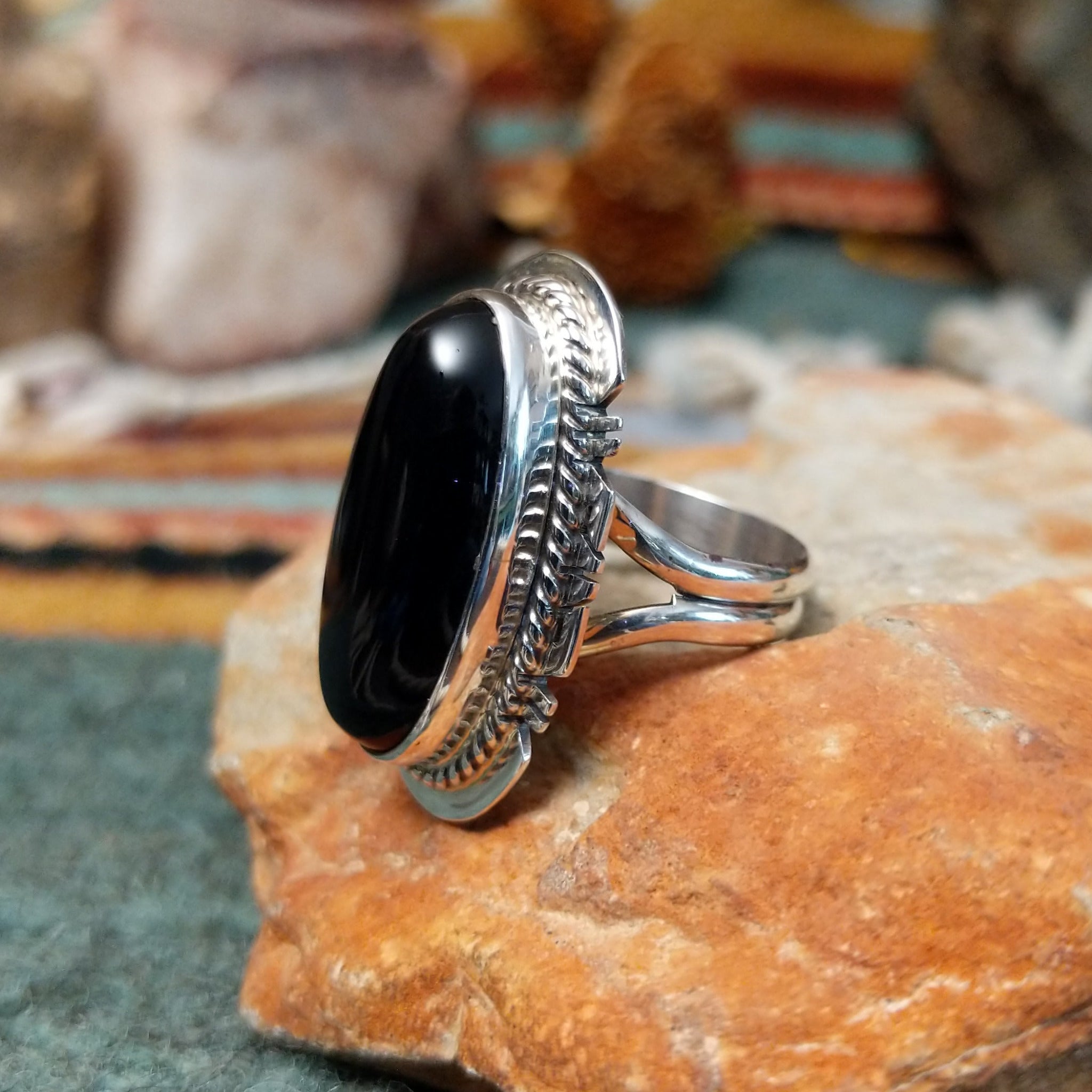 Sterling silver ring by Larson Lee featuring a large elongated oval black onyx cabochon framed by twisted silver rope and geometric silver detailing; side view.