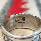 Black Onyx ring by Raymond Coriz featuring a round polished black stone centered in a wide silver band with detailed stamped, radiating, and curved designs; artisan and Sterling Silver stamp.