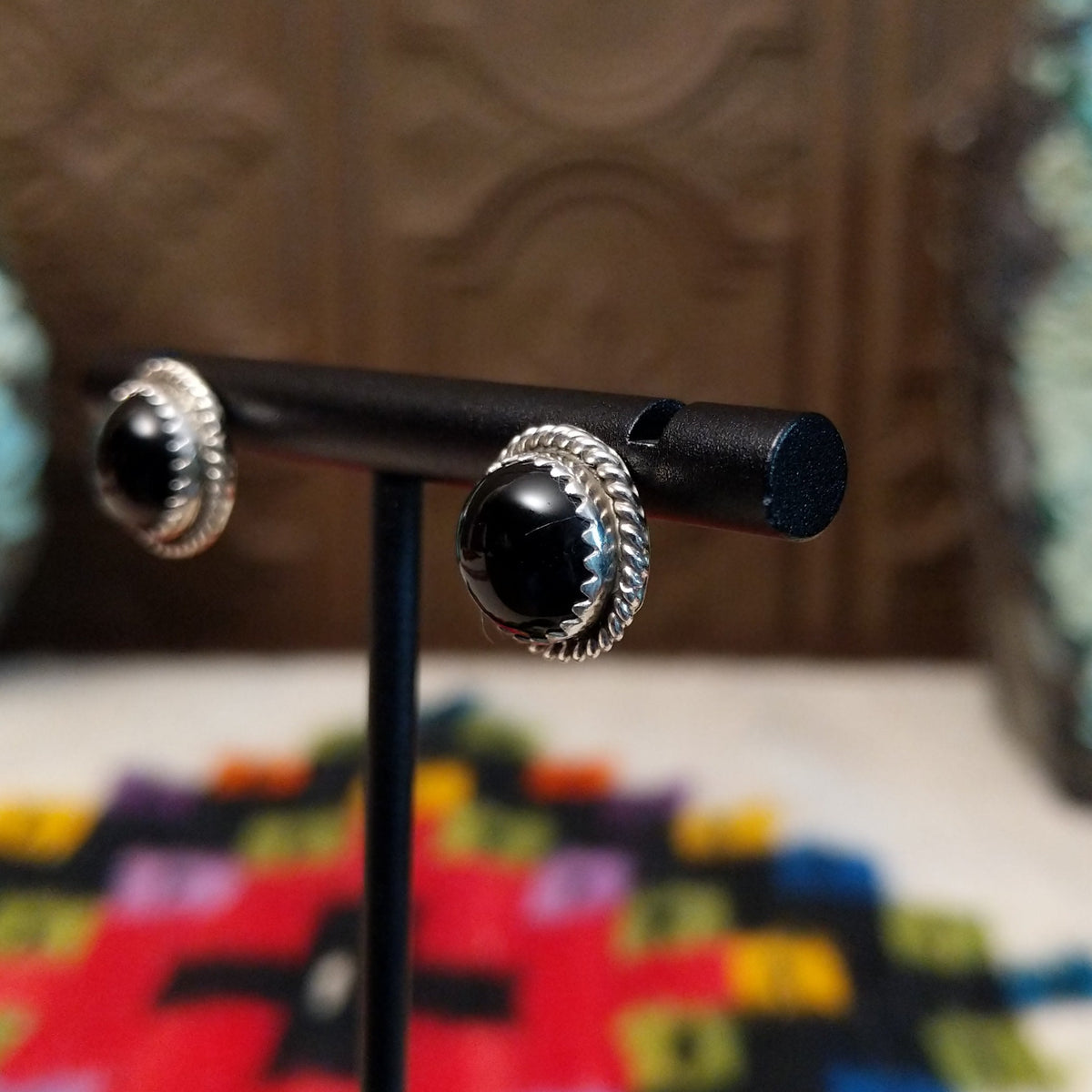 Black Onyx Round Earrings by Peggy Skeets featuring polished round black onyx cabochons set in silver with detailed twisted rope borders; side view.