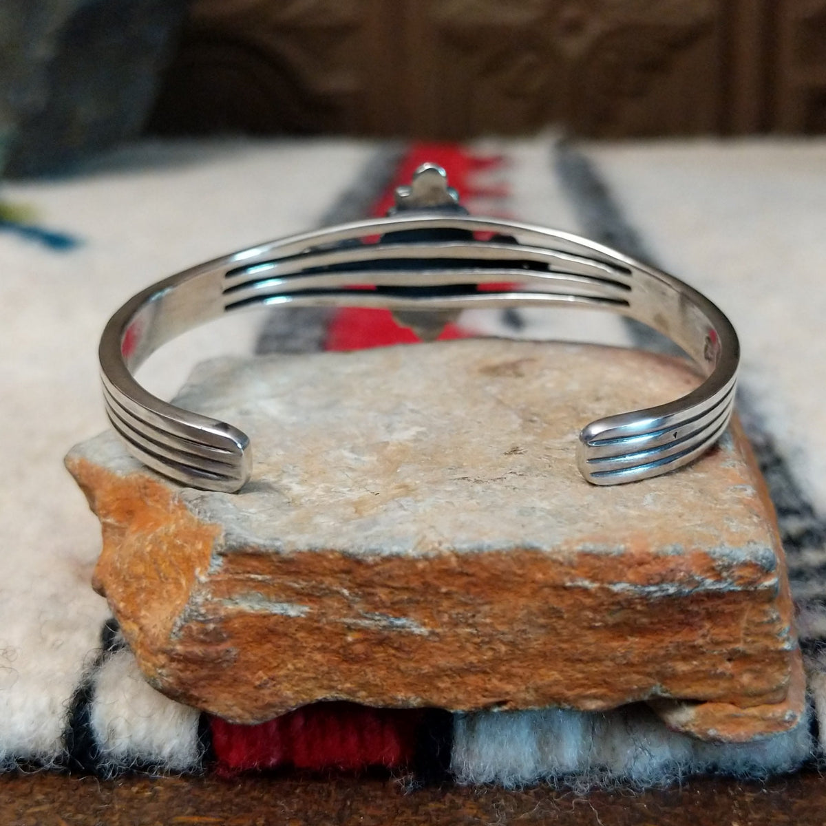 Silver cuff by Raymond Coriz featuring a polished teardrop-shaped black onyx surrounded by twisted wire, silver drops, stamped accents, and layered silver bands; underside view.