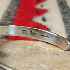 Silver cuff by Raymond Coriz featuring a polished teardrop-shaped black onyx surrounded by twisted wire, silver drops, stamped accents, and layered silver bands; artisan and Sterling Silver stamp.