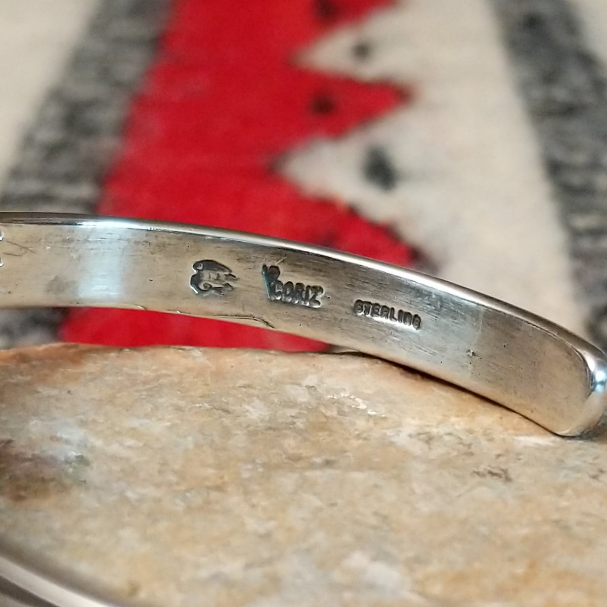 Silver cuff by Raymond Coriz featuring a polished teardrop-shaped black onyx surrounded by twisted wire, silver drops, stamped accents, and layered silver bands; artisan and Sterling Silver stamp.