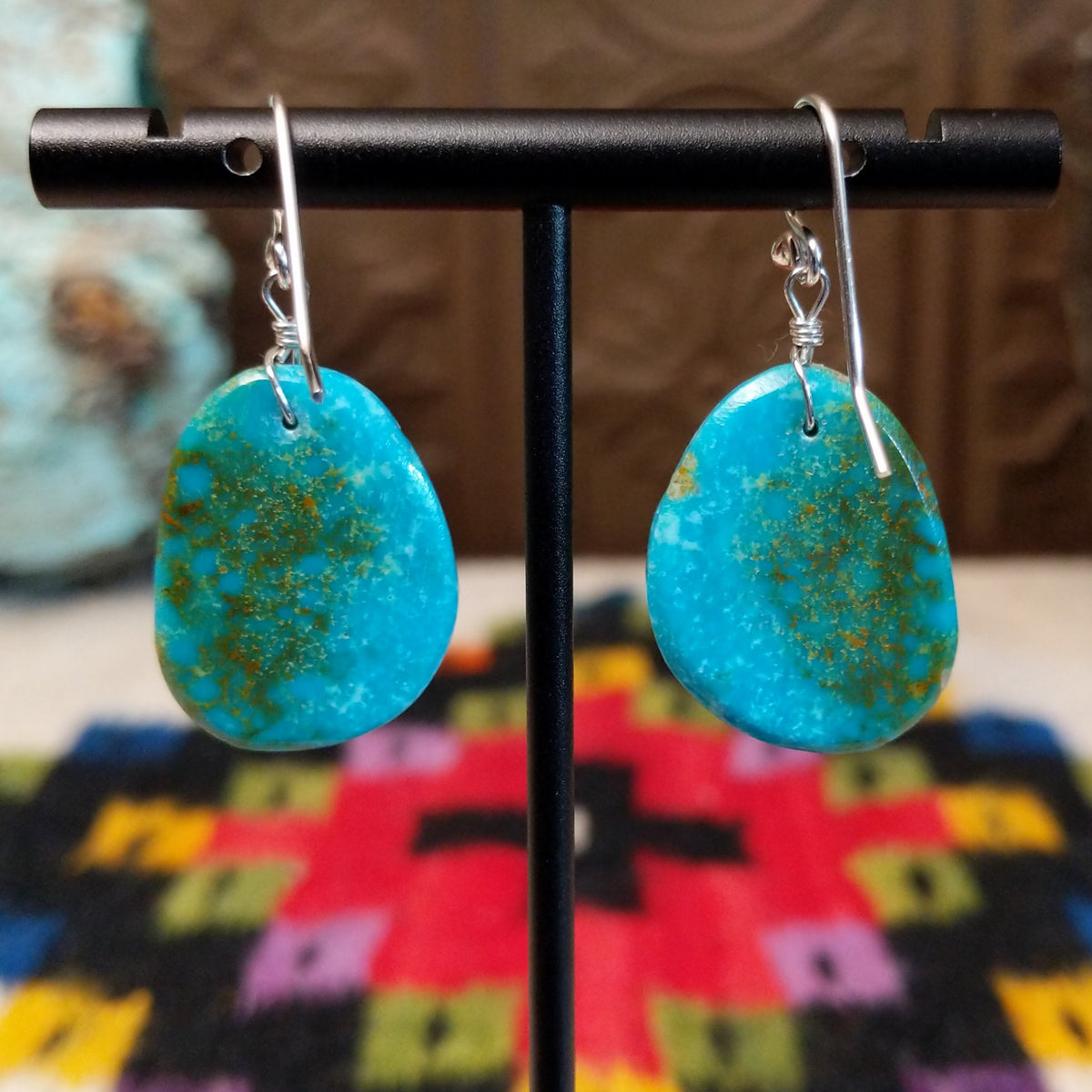 Blue-Green Turquoise Slab Earrings by Ronald Chavez featuring freeform blue-green turquoise stones with natural golden-brown matrix, suspended from silver hooks; backside view.