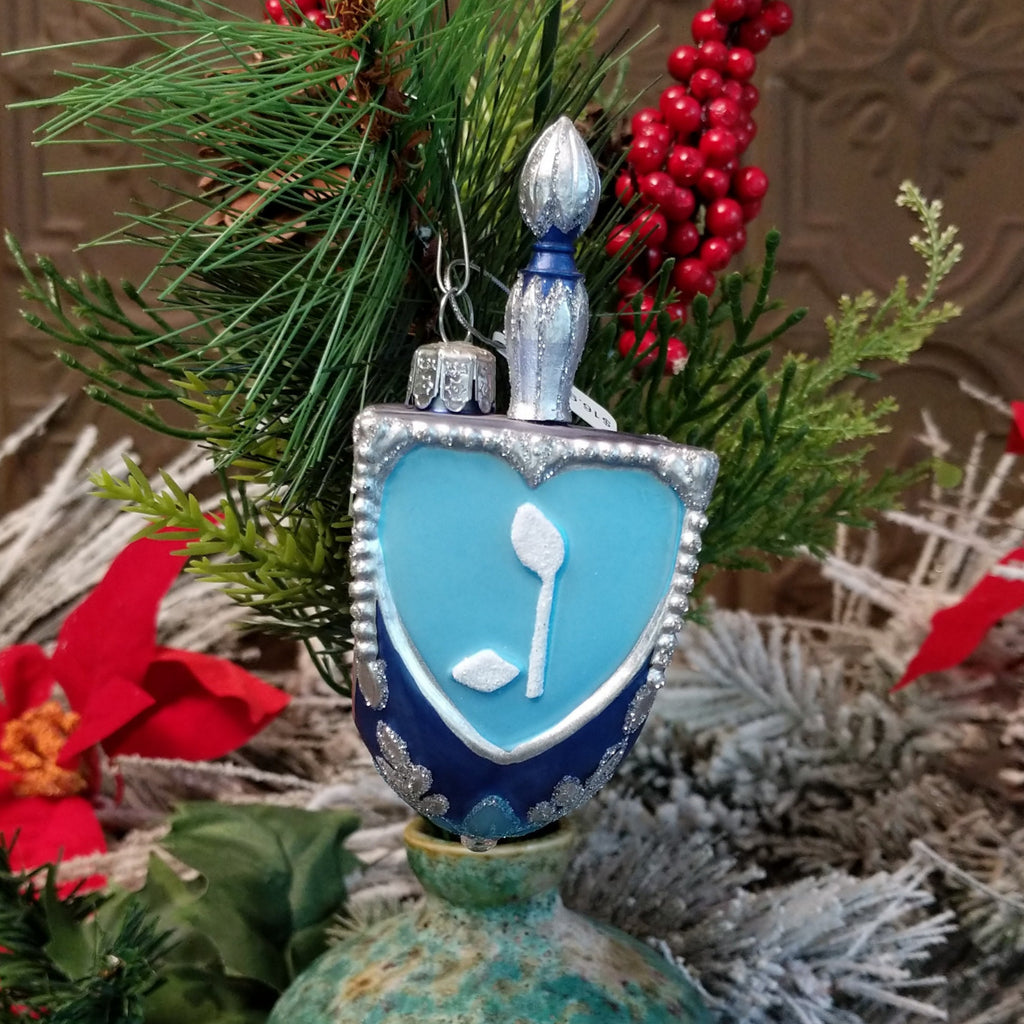 Glass made into a dreidel and painted in various blues, silver, and white with traditional symbols on its form.
