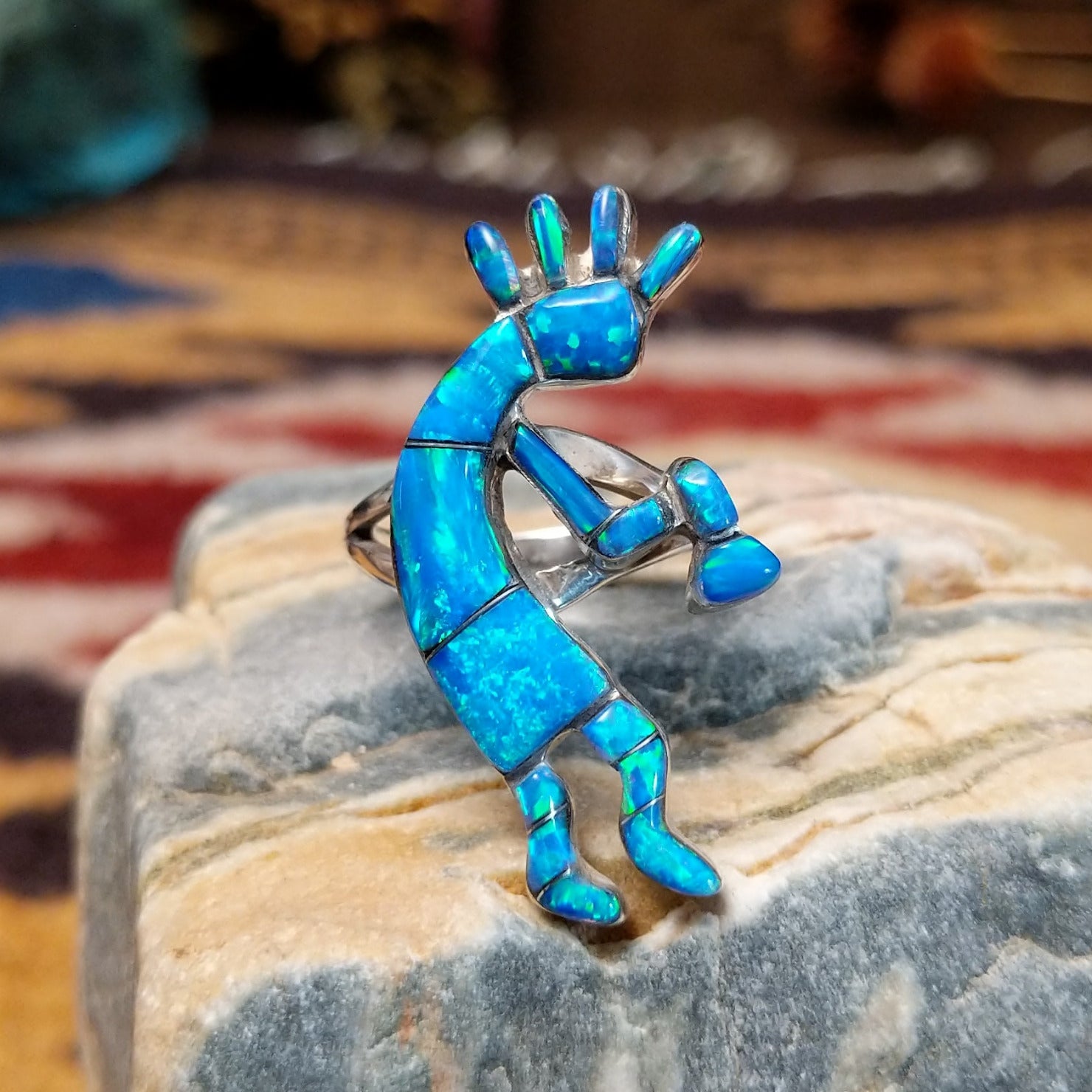 Handcrafted sterling silver ring by James Mason featuring a blue manmade opal and Kokopelli design in a traditional Southwestern Native American style.
