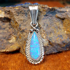 Teardrop-shaped blue man-made opal set in sterling silver with twisted rope and intricate incisions on the frame.