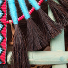 Blue Navajo Bustle artifact reproduction by Linda Lee with beadwork by Dorothy Manning, featuring turquoise, red, black, and white beadwork with dark horsehair accents.