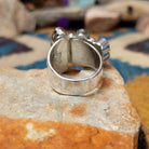 Handcrafted Navajo sterling silver ring by Ann Curley featuring three graduated oval black onyx cabochons in bezel settings with polished silver bead accents on a wide statement band; underside view.