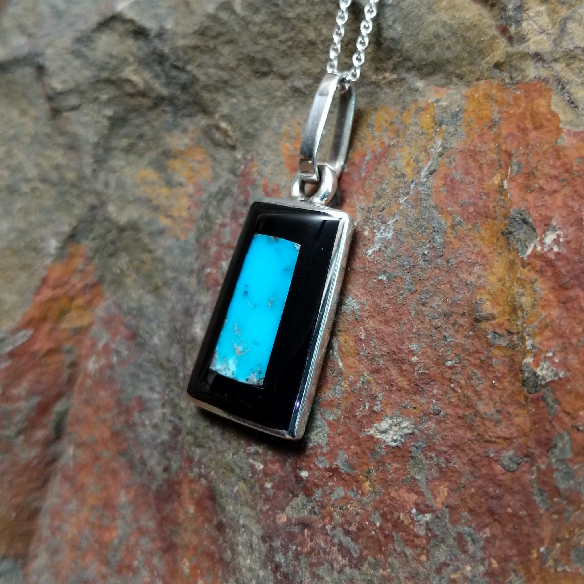 Handcrafted sterling silver turquoise and black onyx inlay pendant by Harlan & Monica Coonsis, featuring a rectangular geometric design; side view.