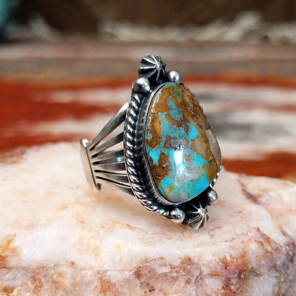 Ornate sterling silver ring with boulder turquoise set in a twisted rope bezel.