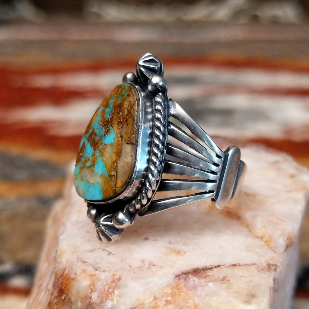 Ornate sterling silver ring with boulder turquoise set in a twisted rope bezel.