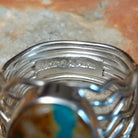 Boulder Turquoise Strand Ring by Angela Martin featuring a natural turquoise stone set in sterling silver, size 8, approximately 0.75 inches long and 0.875 inches wide. Handcrafted jewelry piece with distinctive turquoise patterns; artisan and Sterling Silver stamp.