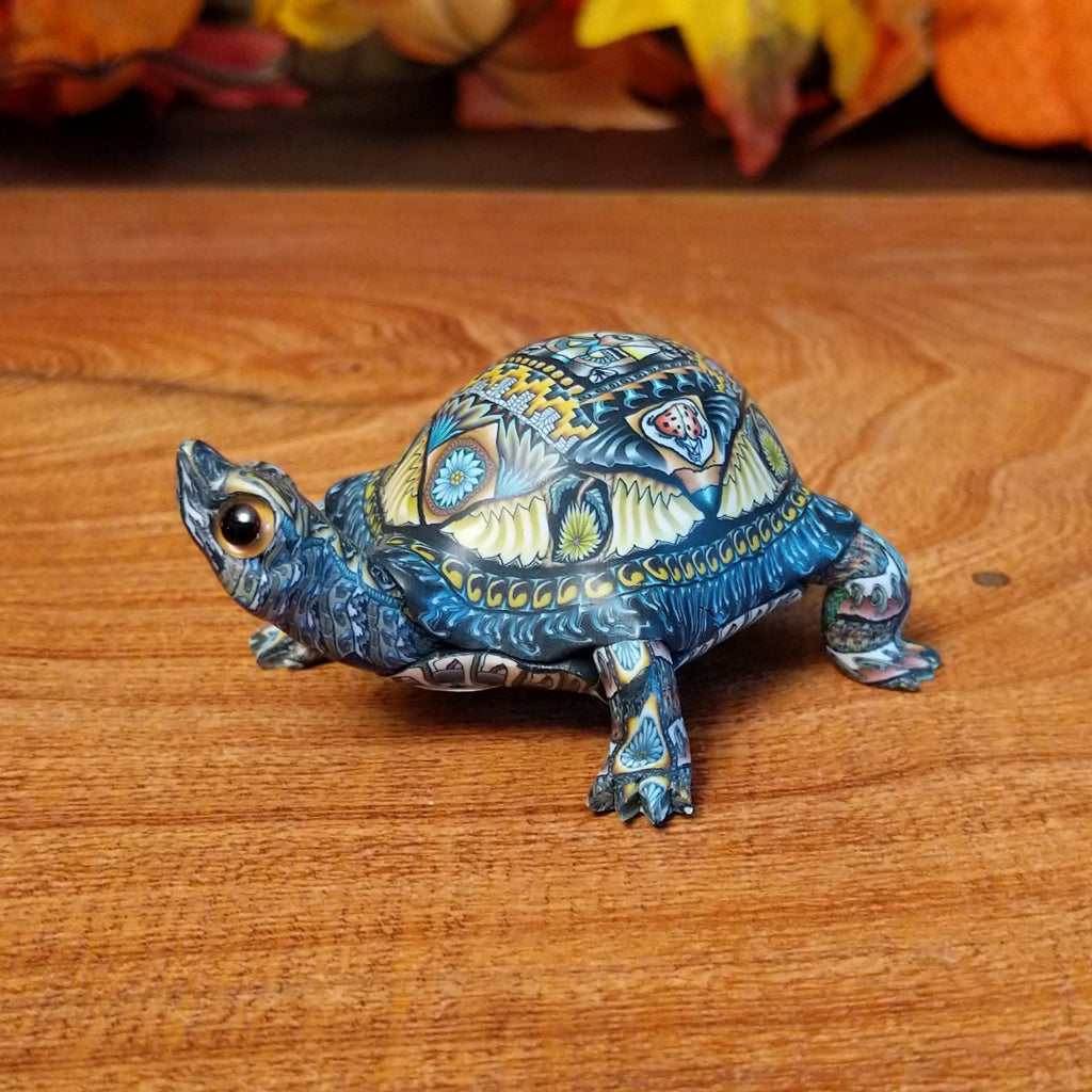 Polymer clay used to create a detailed box turtle with vibrant insect and floral motifs.
