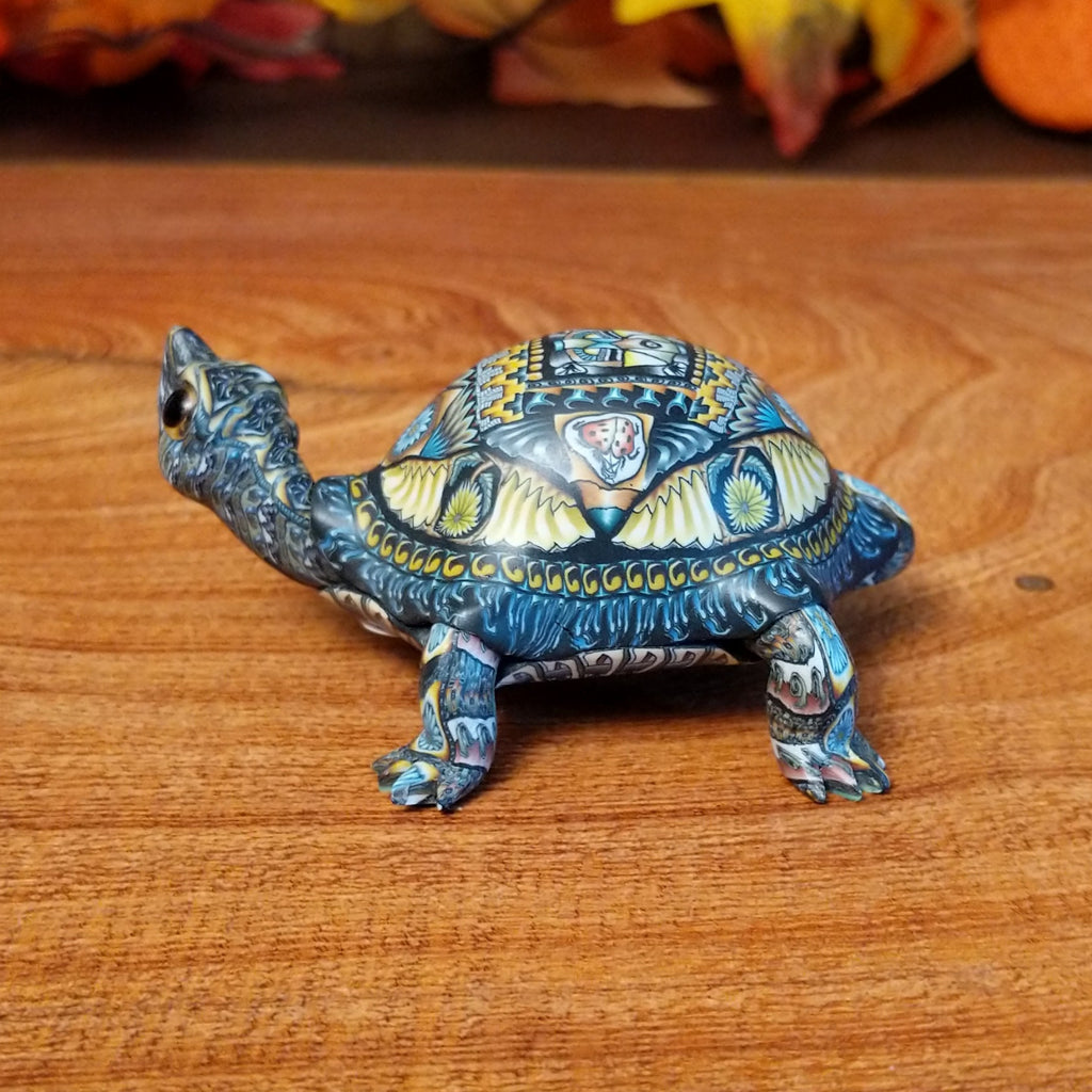 Polymer clay used to create a detailed box turtle with vibrant insect and floral motifs.