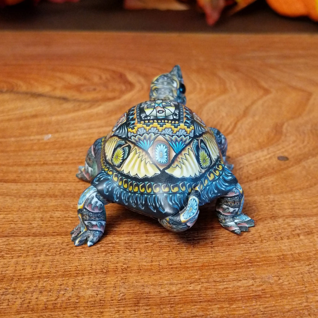 Polymer clay used to create a detailed box turtle with vibrant insect and floral motifs.
