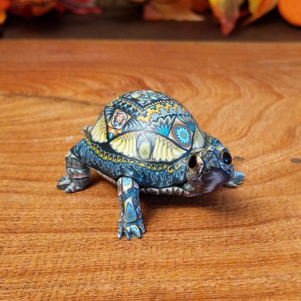 Polymer clay used to create a detailed box turtle with vibrant insect and floral motifs.